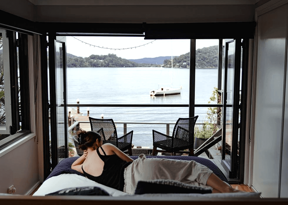 A woman laying on a bed that overlooks a riverview.